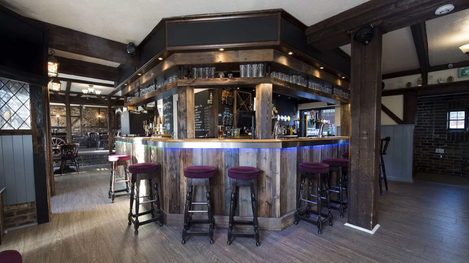 The open plan bar at The Stags Head with timber beams and bar stools
